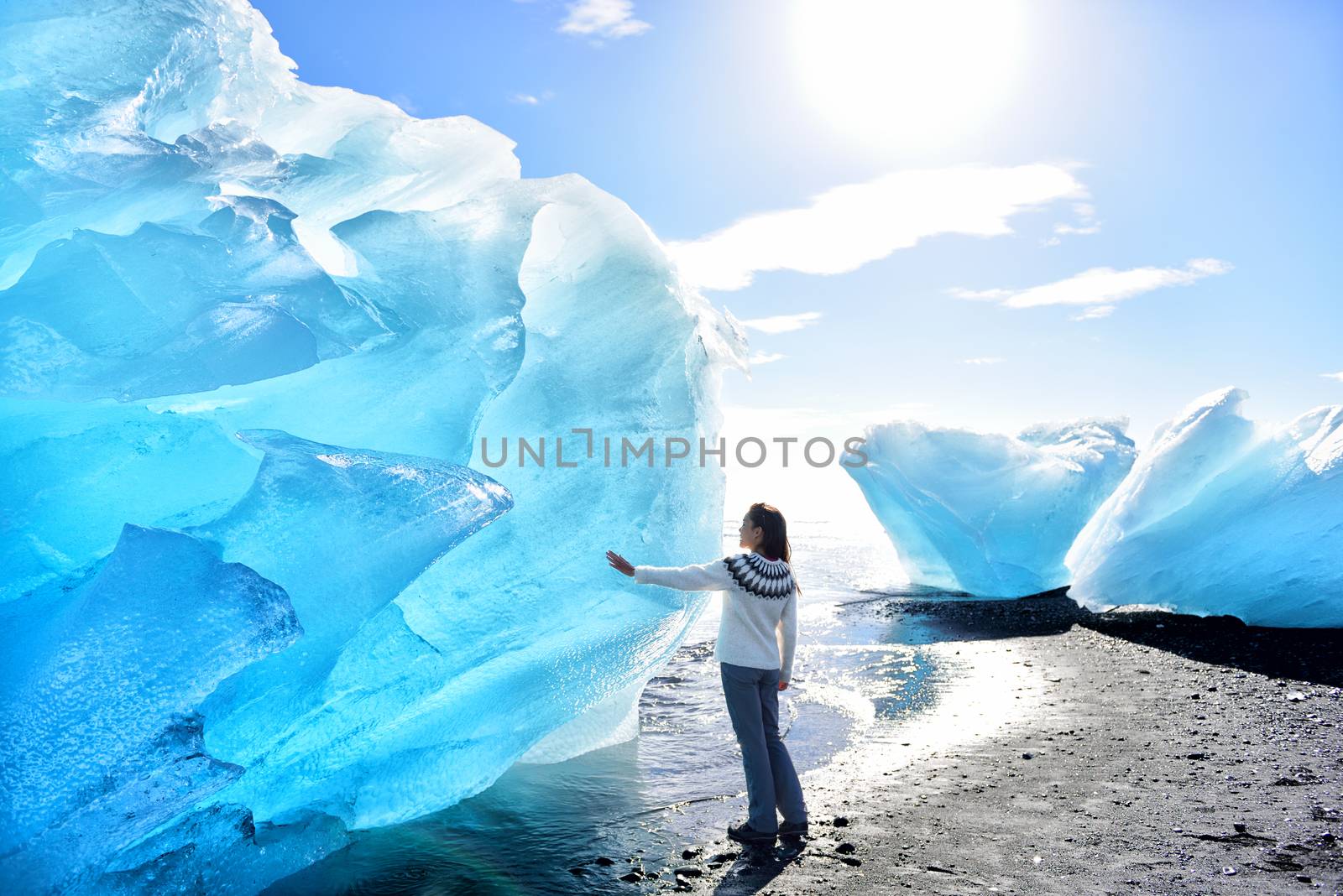 Iceland Amazing landscape at Iceberg beach. Tourist by icebergs on Ice beach, Breidamerkursandur aka Diamond Beach by jokulsarlon glacial lagoon / glacier lake nature. Woman in icelandic sweater by Maridav