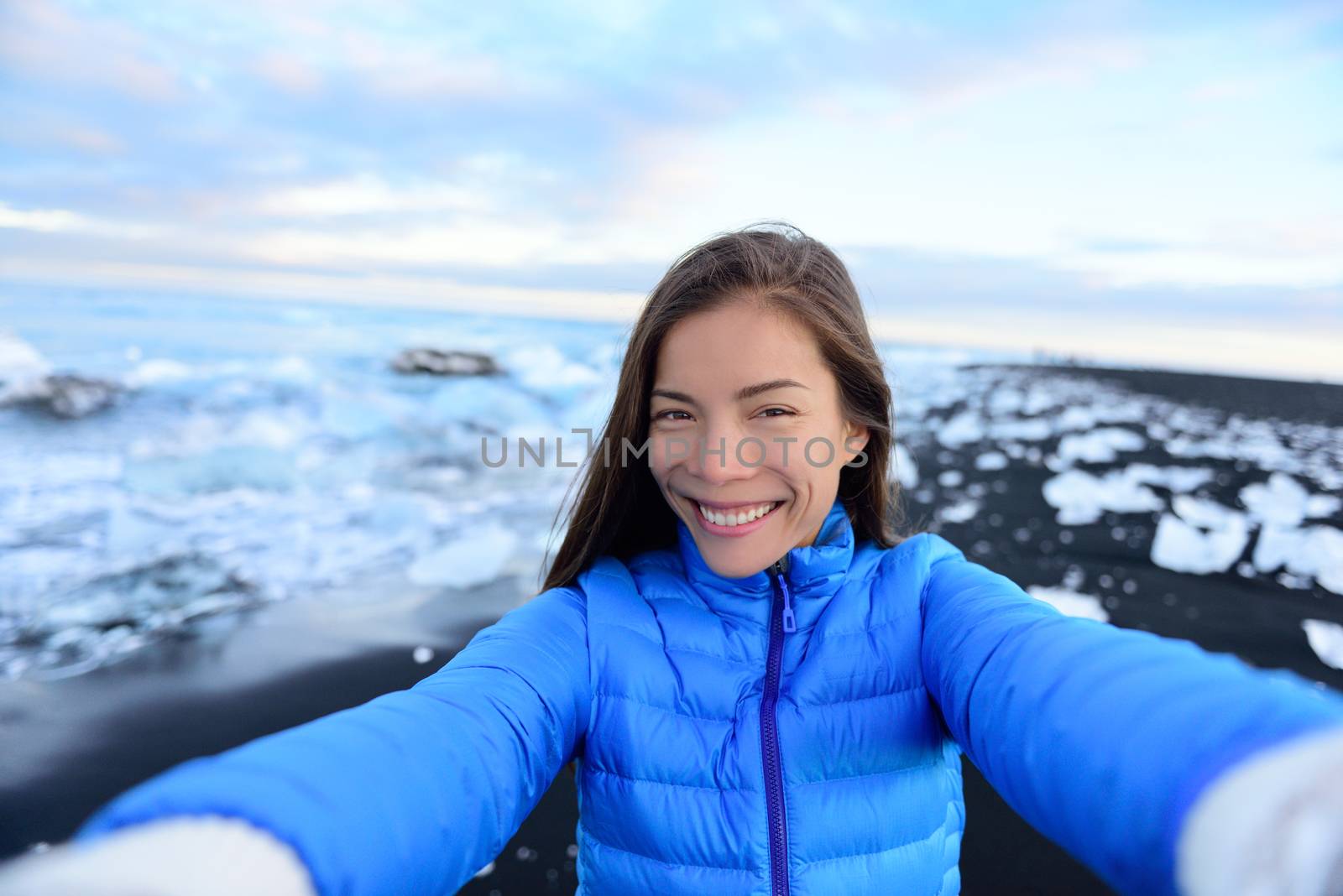 Adventure selfie by trave explorer woman on Iceland Diamond Beach. Woman tourist in amazing landscape Ice beach, Breidamerkursandur by jokulsarlon glacial lagoon / glacier lake nature.
