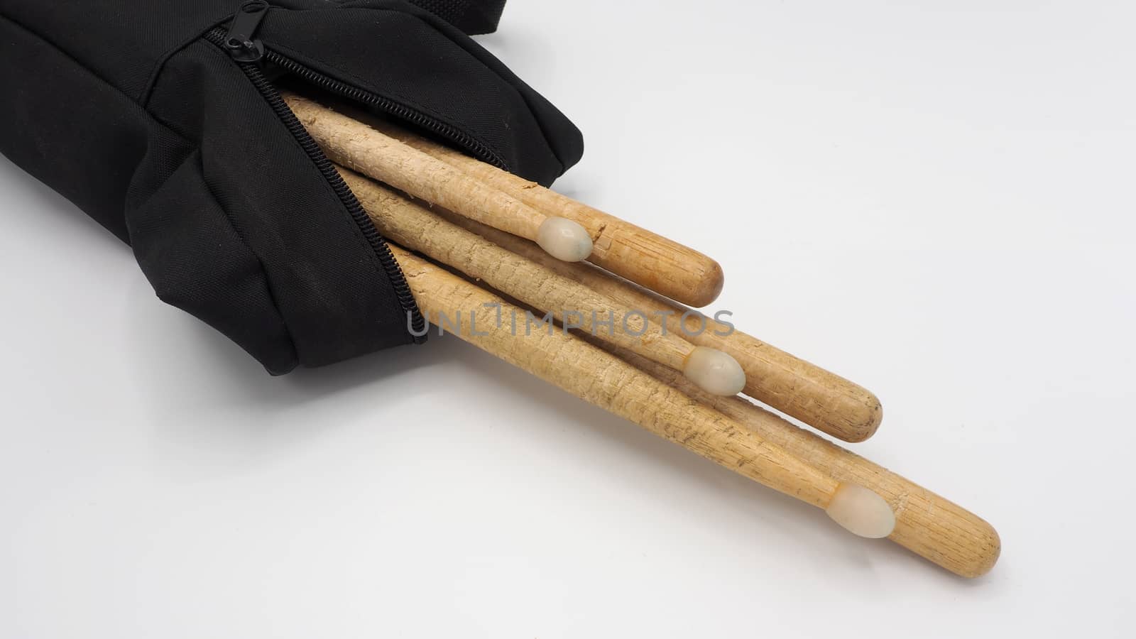 Drum sticks which made from real wood material and black color fabric bags with zip on white background and isolated studio shot.