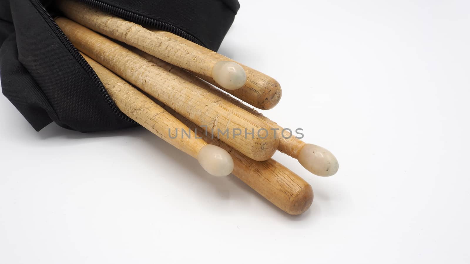 Drum sticks which made from real wood material and black color fabric bags with zip on white background and isolated studio shot.