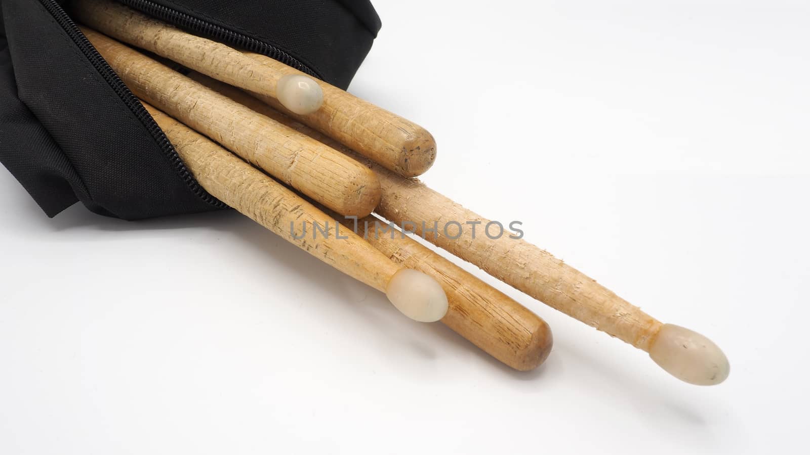 Drum sticks which made from real wood material and black color fabric bags with zip on white background and isolated studio shot.