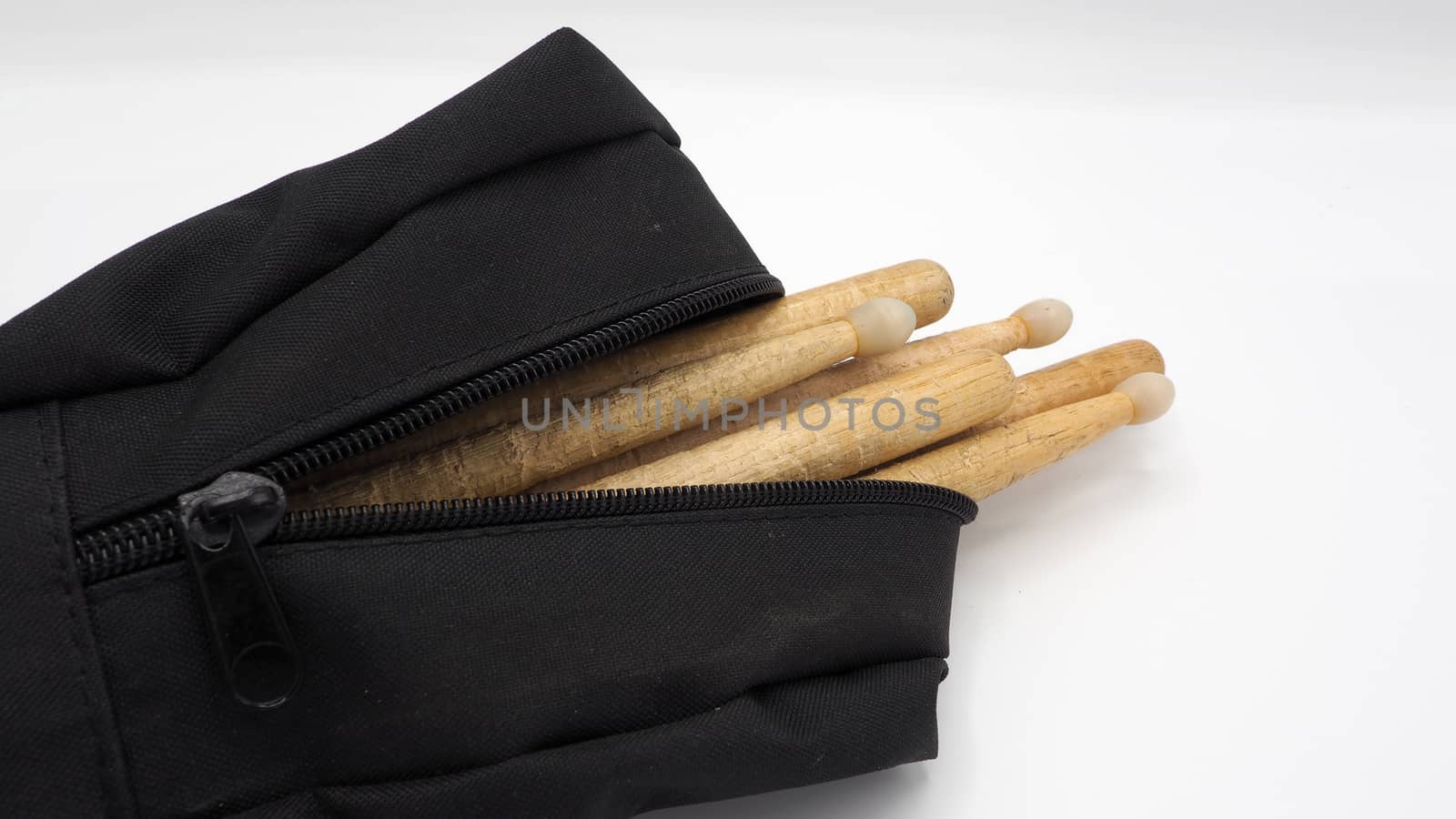 Drum sticks which made from real wood material and black color fabric bags with zip on white background and isolated studio shot.