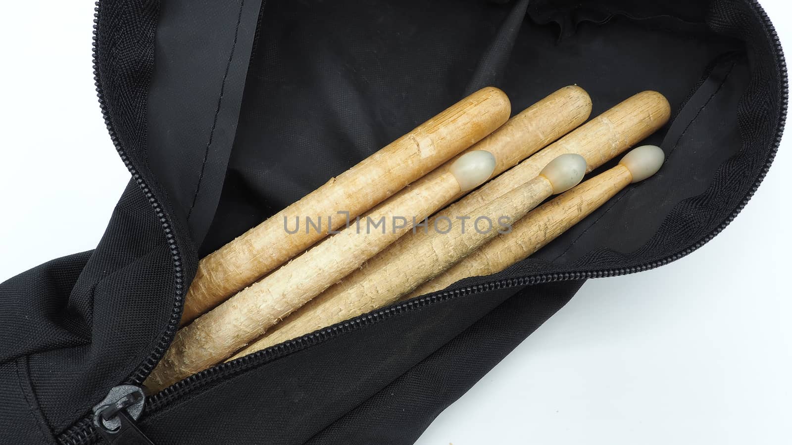 Drum sticks which made from real wood material and black color fabric bags with zip on white background and isolated studio shot.