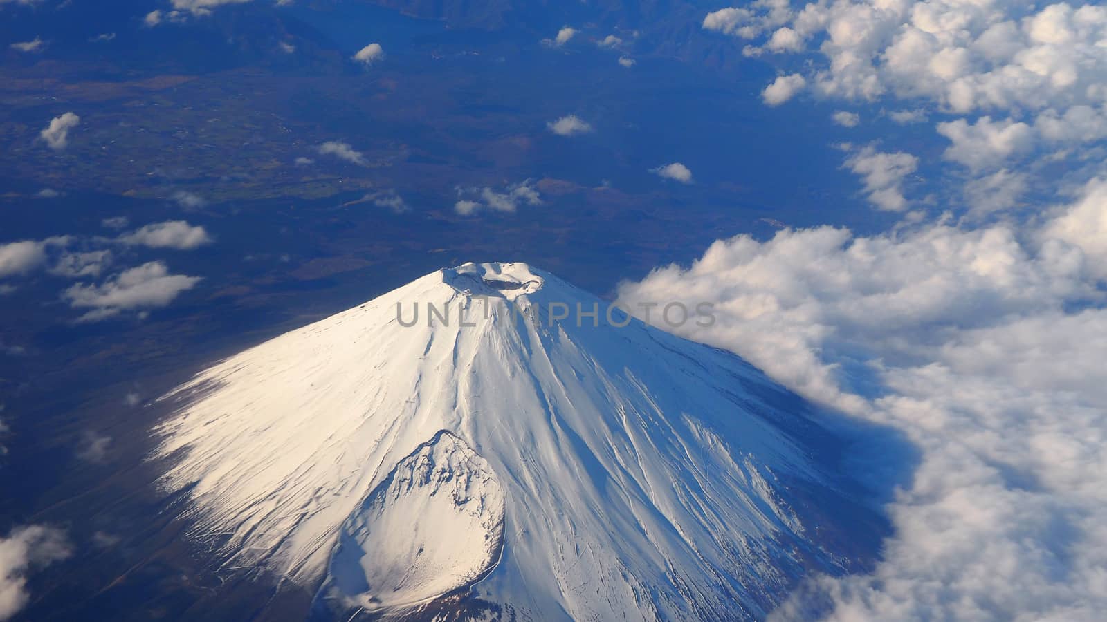 Rare images top view angle of Mt. Fuji mountain and white snow cover on it and light clouds and clear clean blue sky which shoot from airplane.