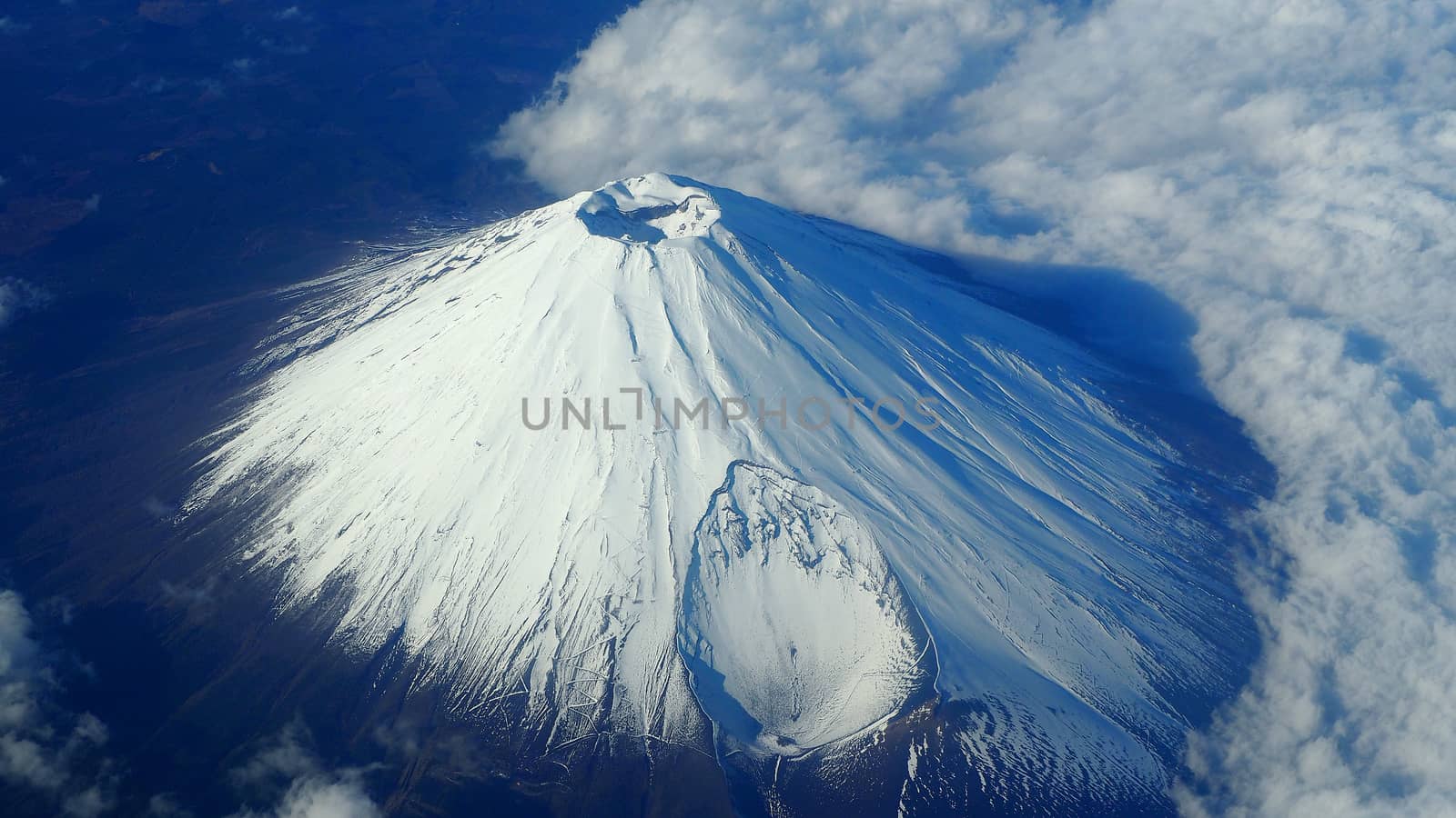 Rare images top view angle of Mt. Fuji mountain and white snow cover on it and light clouds and clear clean blue sky which shoot from airplane.