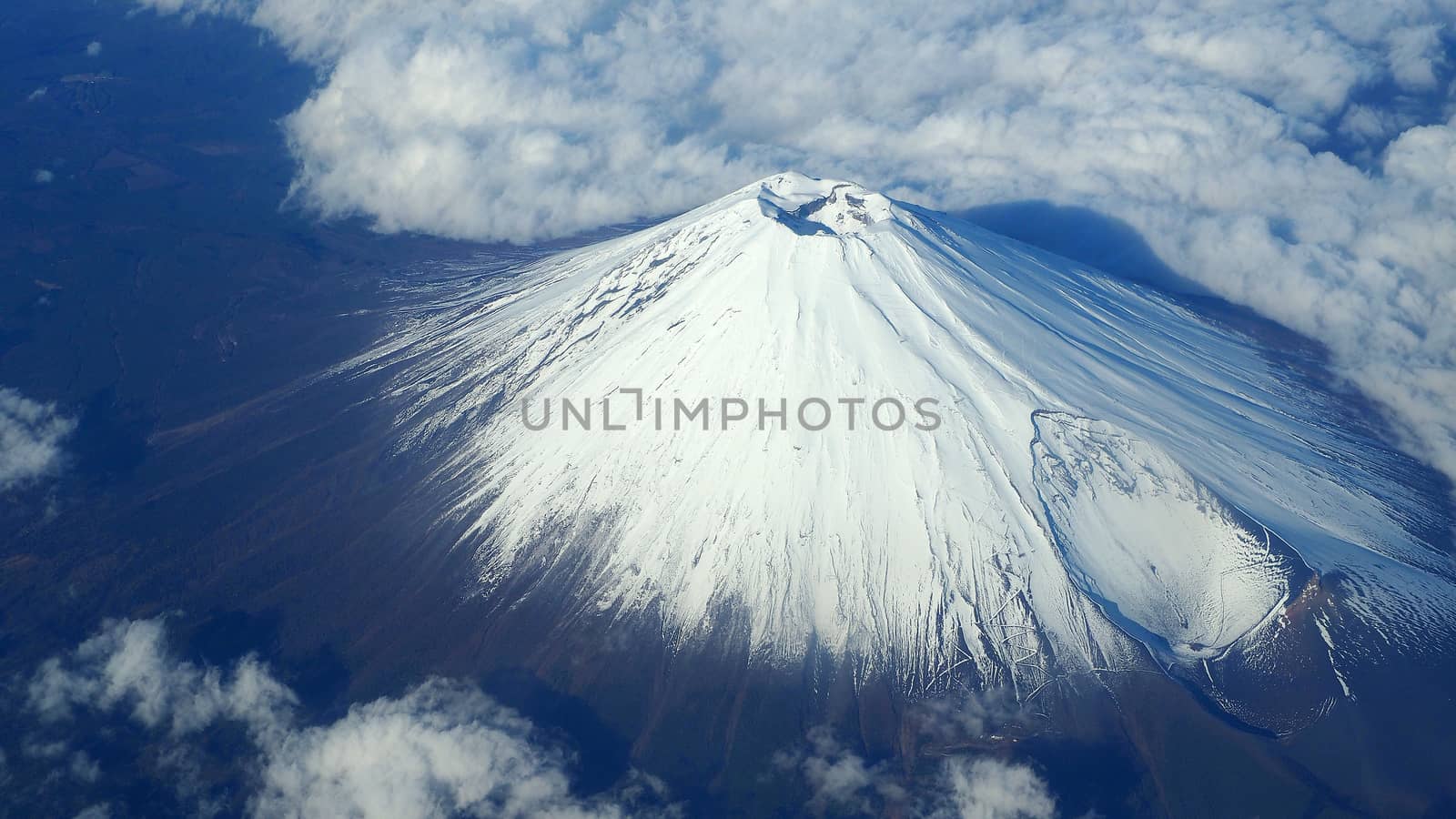 Rare images top view angle of Mt. Fuji mountain and white snow cover on it and light clouds and clear clean blue sky which shoot from airplane.