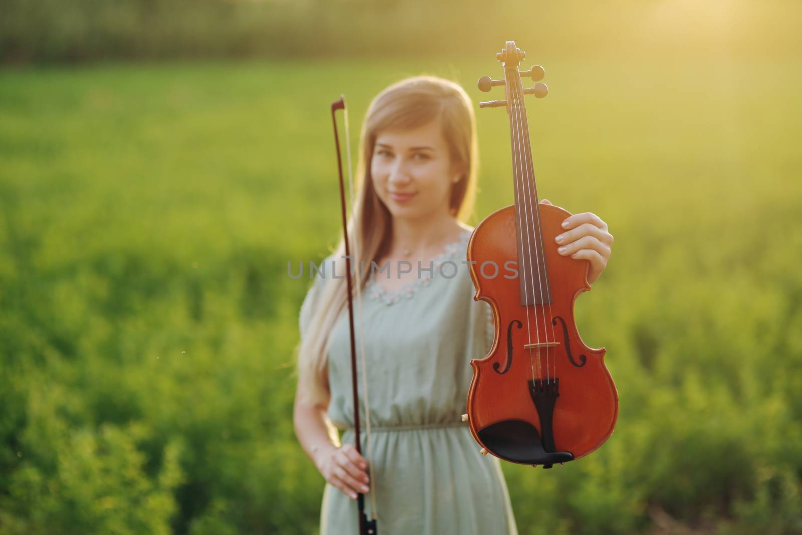 Violin in the hands of a young female violinist in the sunset light.  by selinsmo