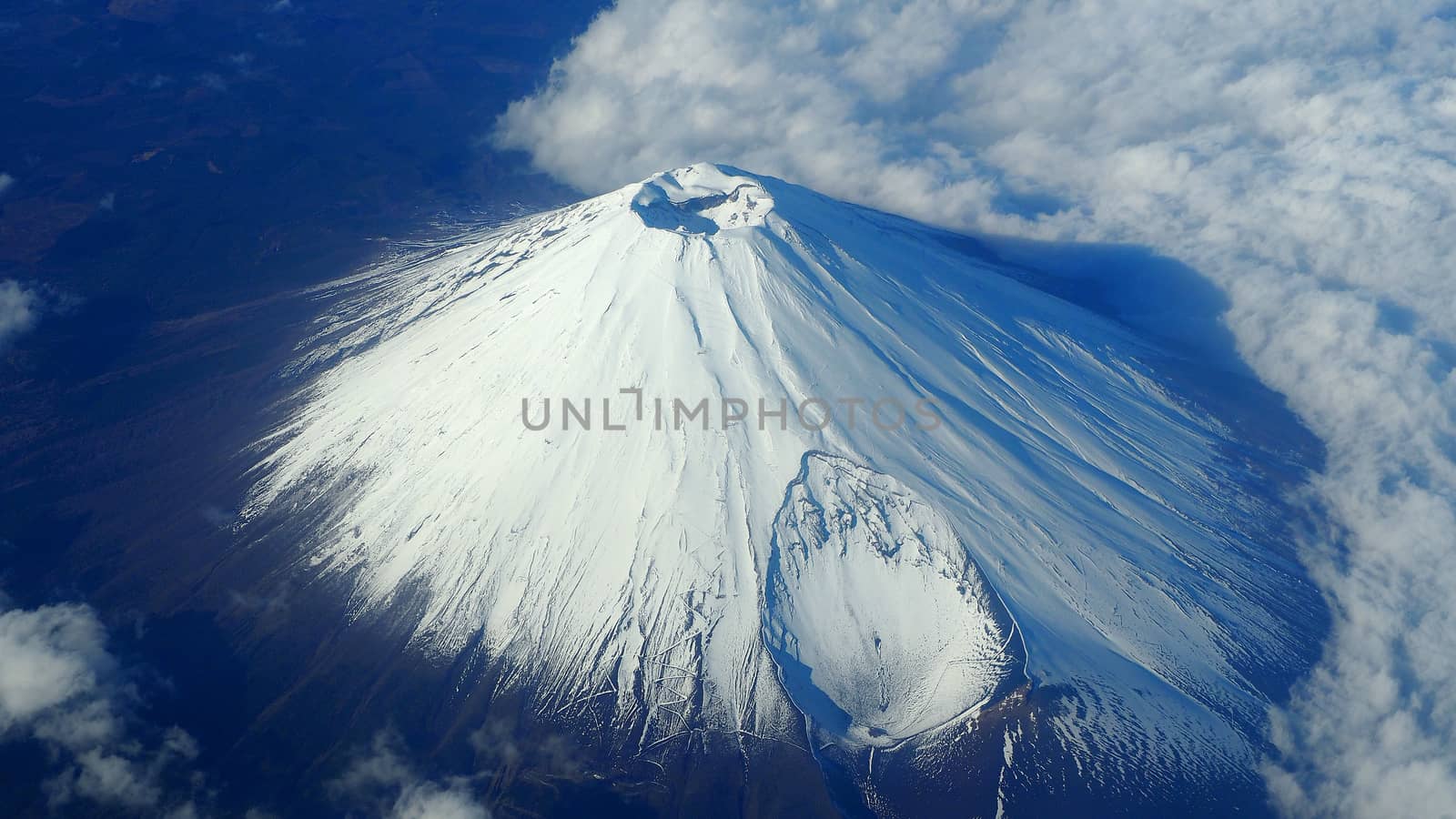 Rare images top view angle of Mt. Fuji mountain and white snow cover on it and light clouds and clear clean blue sky which shoot from airplane.