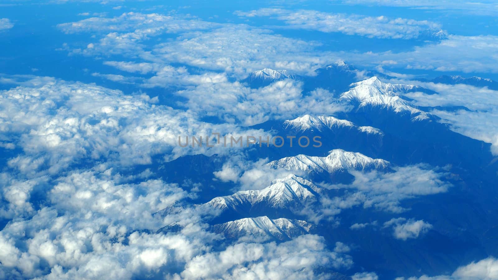 Top view angle images of snow hills around Fuji mountain and white light clouds and blue sky in Tokyo Japan which shoot from airlane.