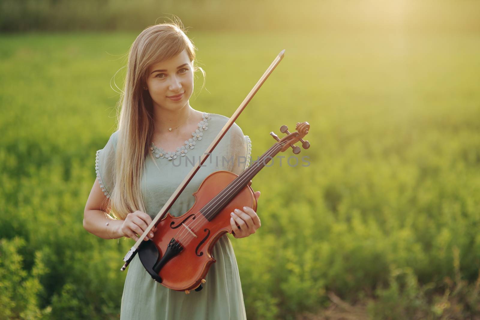 Female musician violinist holding a violin in her hands in sunset light. Violin training concept