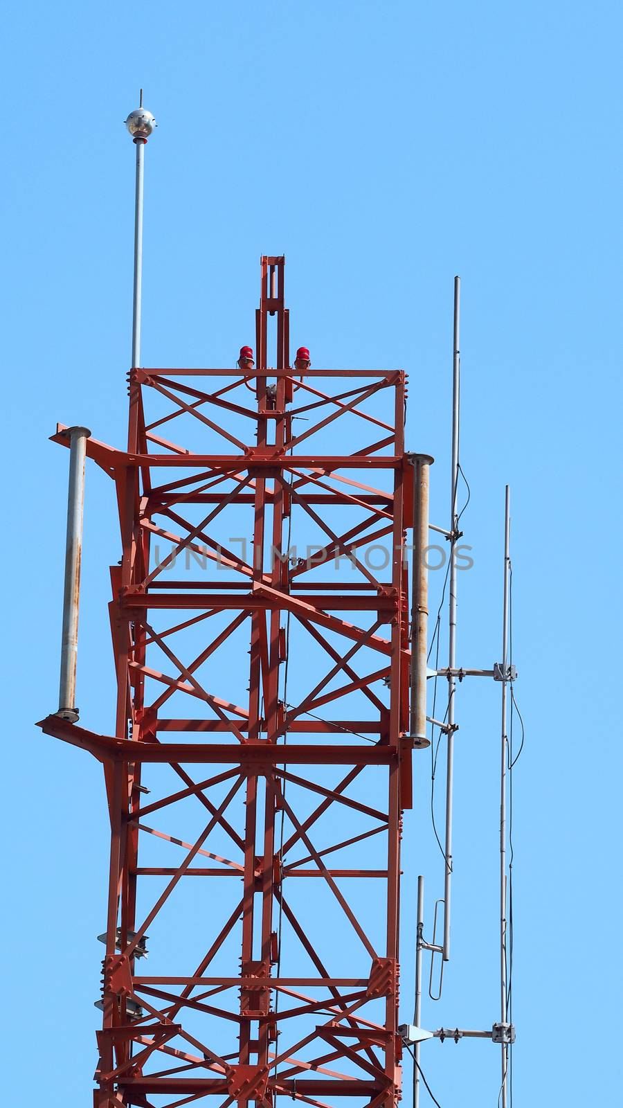 Telecommunication tower closeup and red color and blue sky.