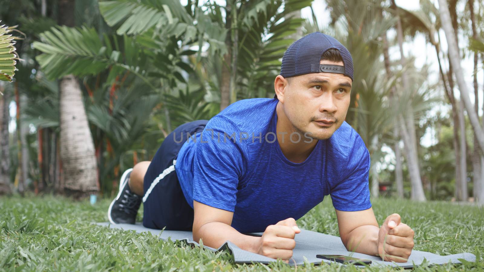 Mature Asian man fit and plank exercise on the grass in the park. sportsman wearing sportswear, fitness, and training outdoors. Sport and healthy for a balanced life