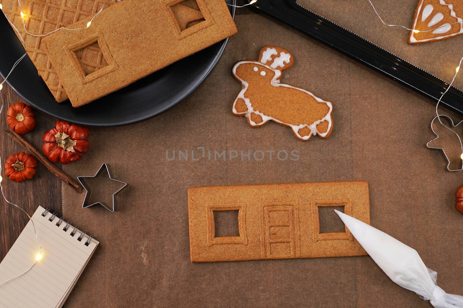 Young woman is decorating Christmas Gingerbread House cookies bi by ROMIXIMAGE