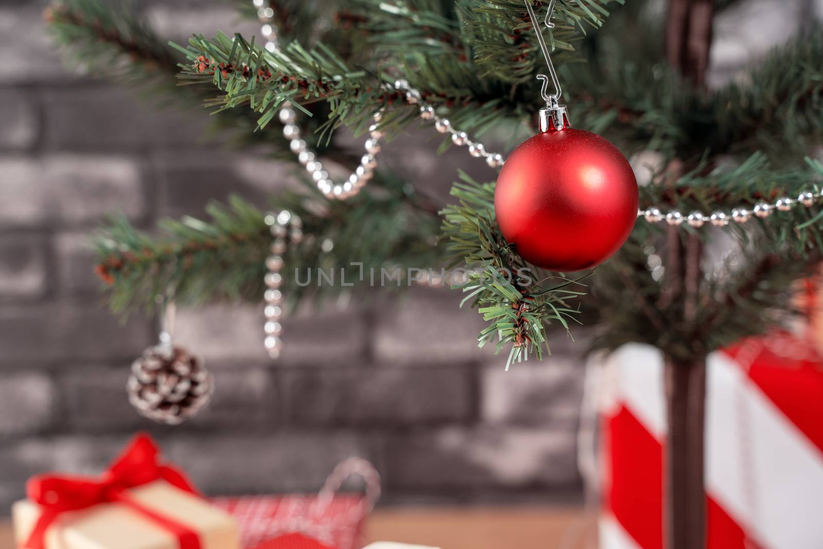 Decorated Christmas tree with wrapped beautiful red and white gifts at home with black brick wall, festive design concept, close up.