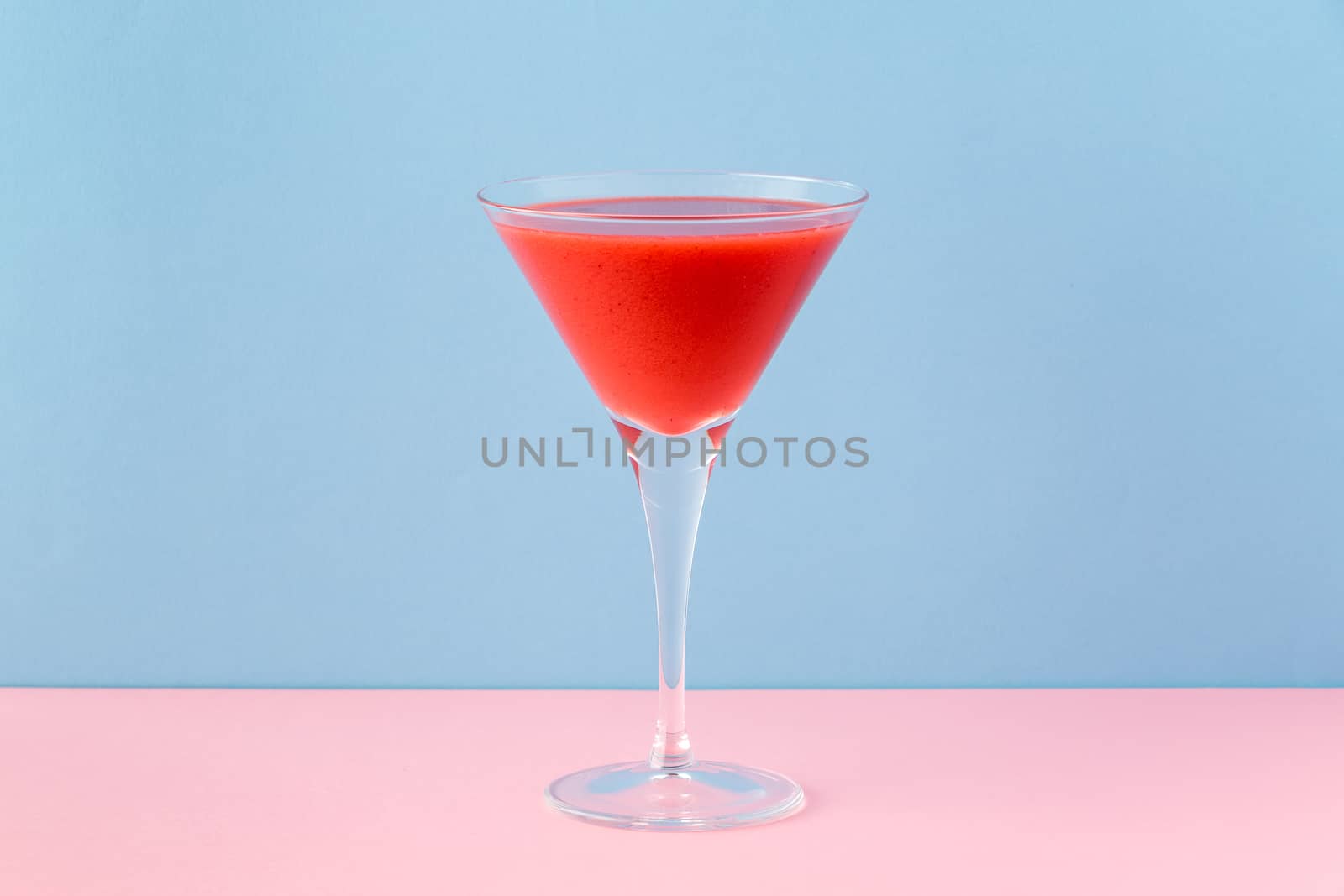 Strawberry smoothie cup on a pink and light blue background. Minimalist image.