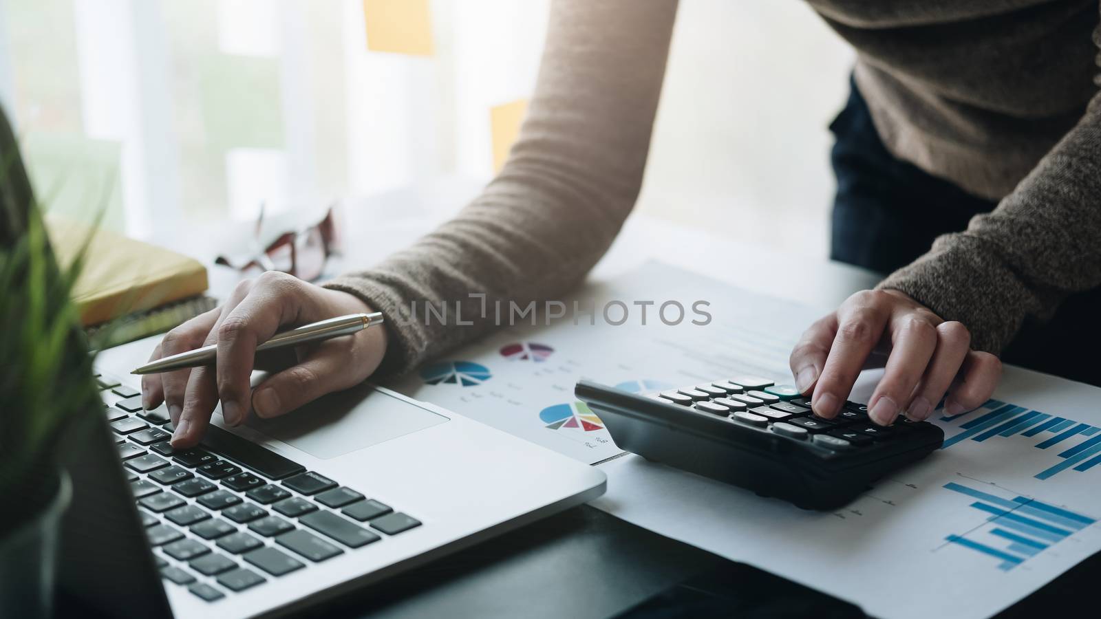 Business woman working in finance and accounting Analyze financial budget with calculator in the office.