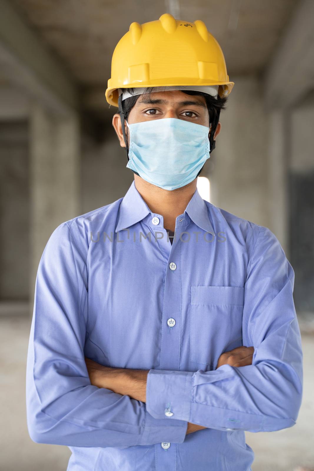 Concept of back to work, opening of construction sites - portrait of confident male construction worker in a construction helmet with medical mask due to coronavirus or covid-19 pandemic