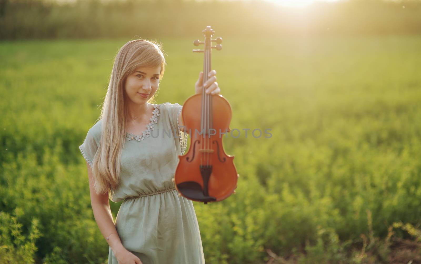 Female musician violinist holding a violin in her hands in sunset light. Violin training concept