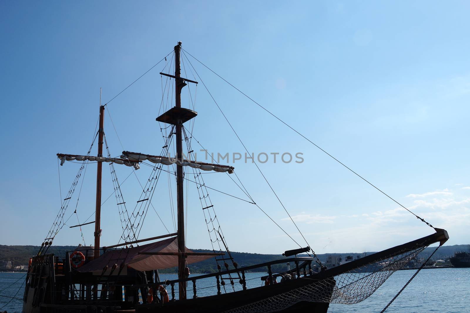 deck of an old ship with masts against a blue sunset sky.