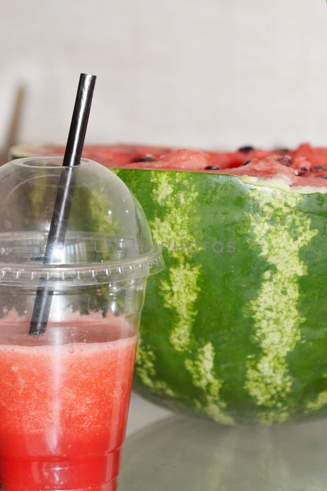 fresh watermelon in a glass with a straw and half a watermelon lose-up