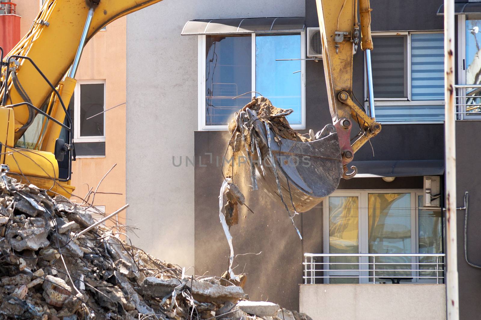 an excavator with a bucket breaks an old residential building by Annado