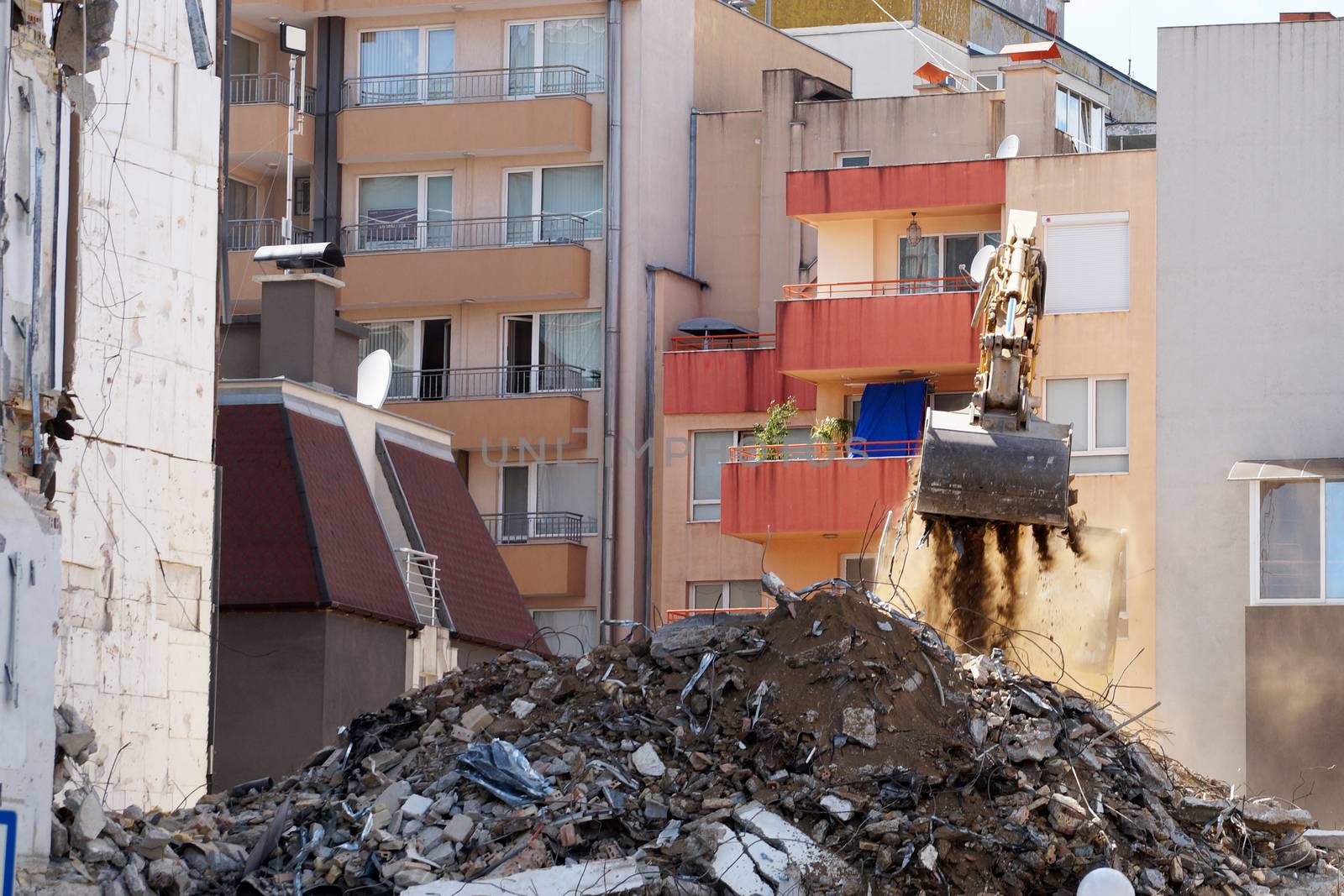 an excavator with a bucket breaks an old residential building by Annado