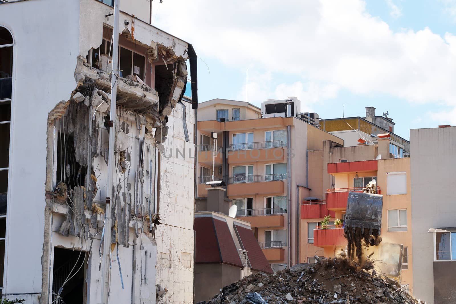 an excavator with a bucket breaks an old residential building.