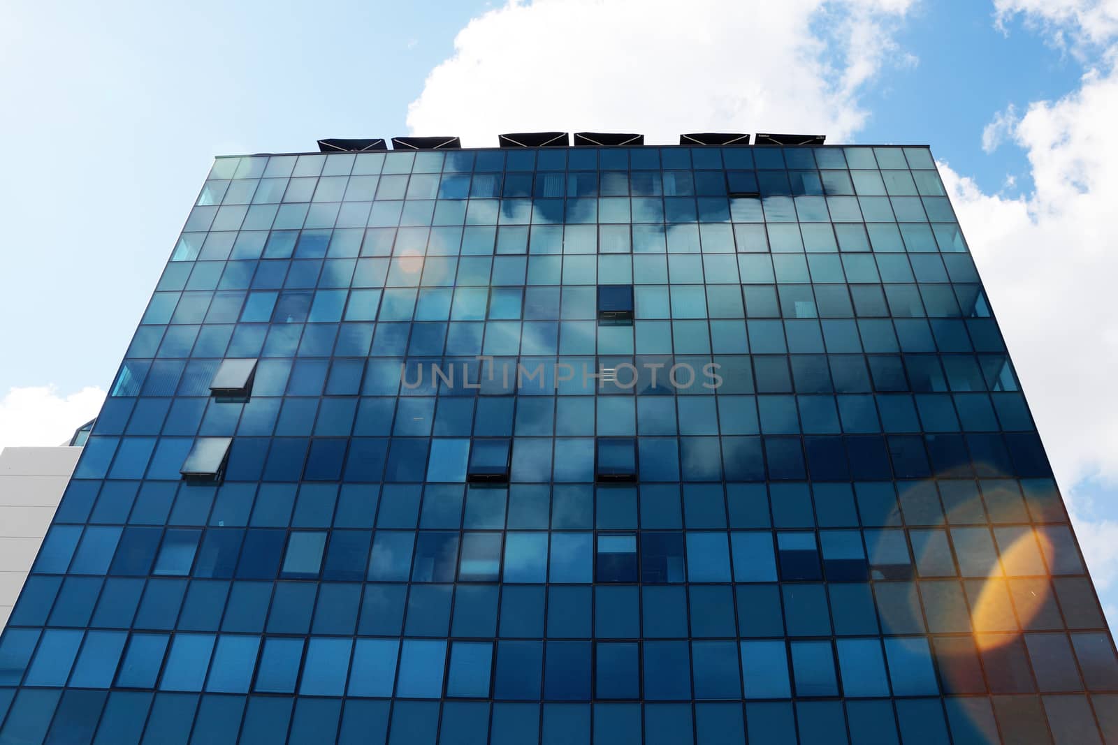 Clouds reflected in the glass facade of a skyscraper by Annado