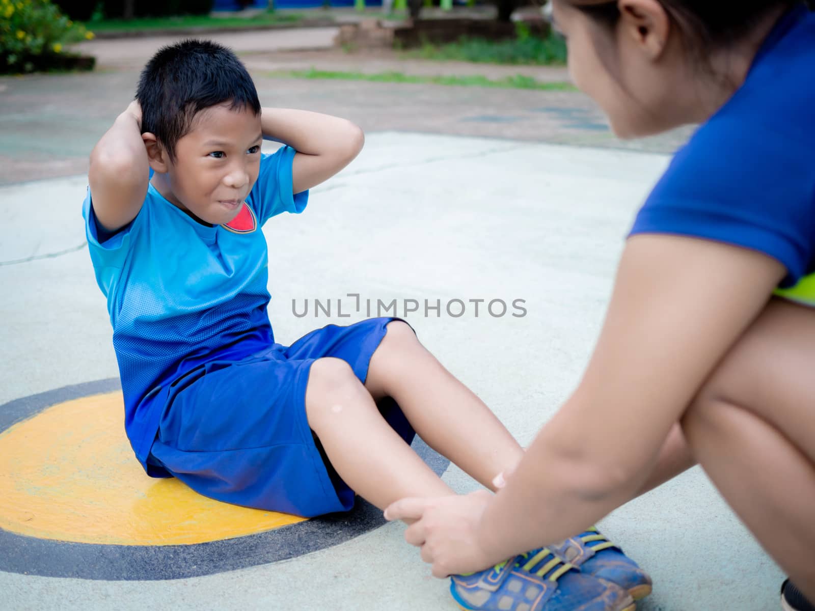 A boy exercising with his mother's support. by Unimages2527