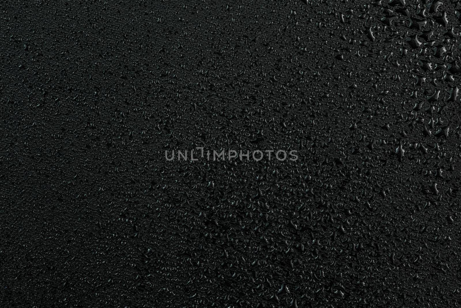 dark abstract background of water drops on flat black rubber surface