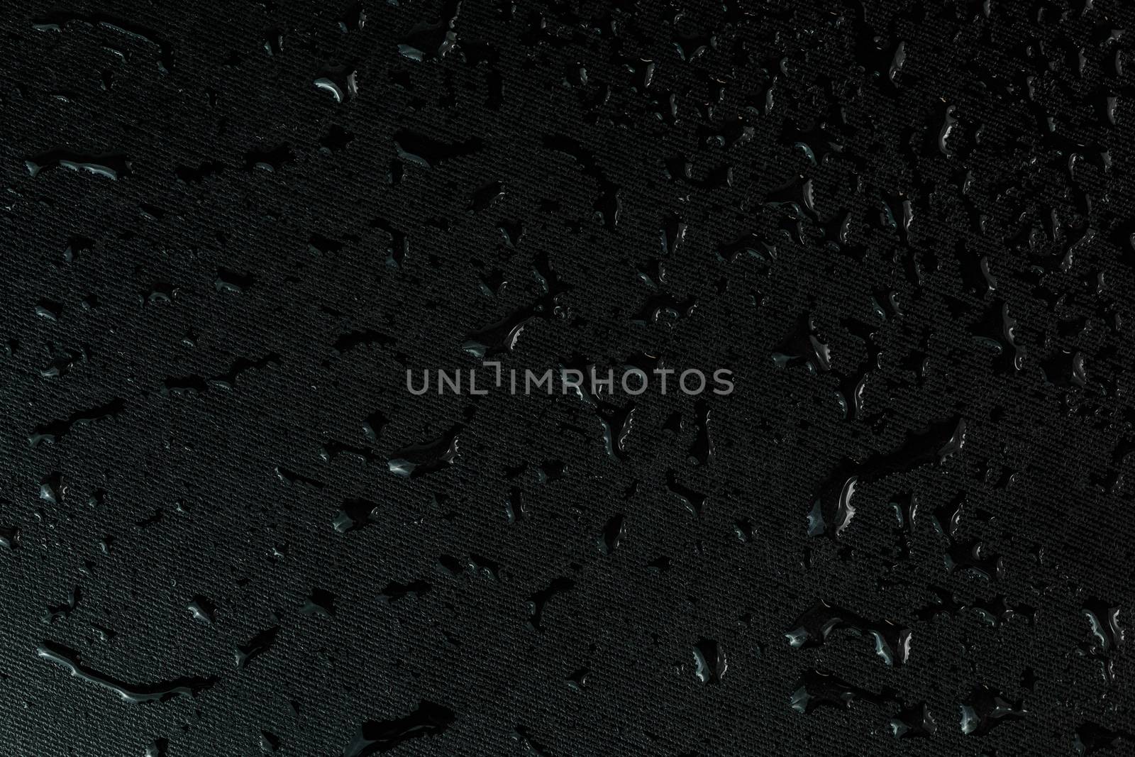 macro background of black flat rubber surface with water drops.