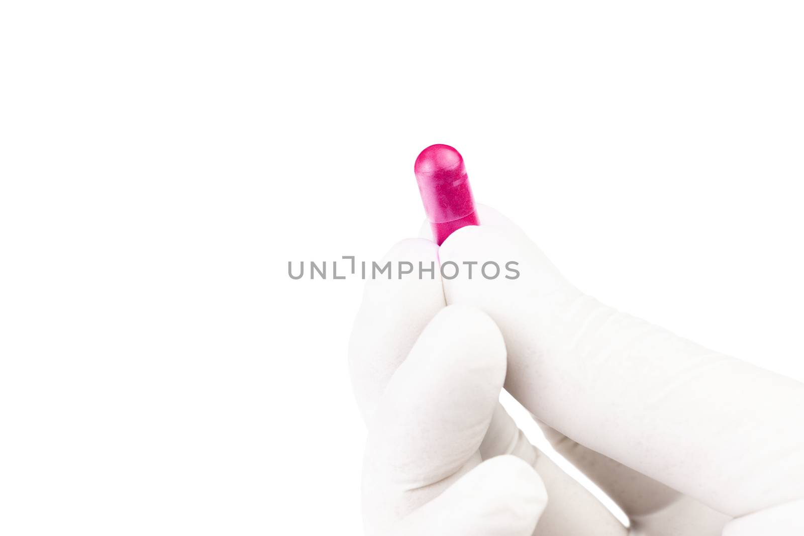 hand in medical glove holding plastic pink color organic med capsule isolated on white background closeup.