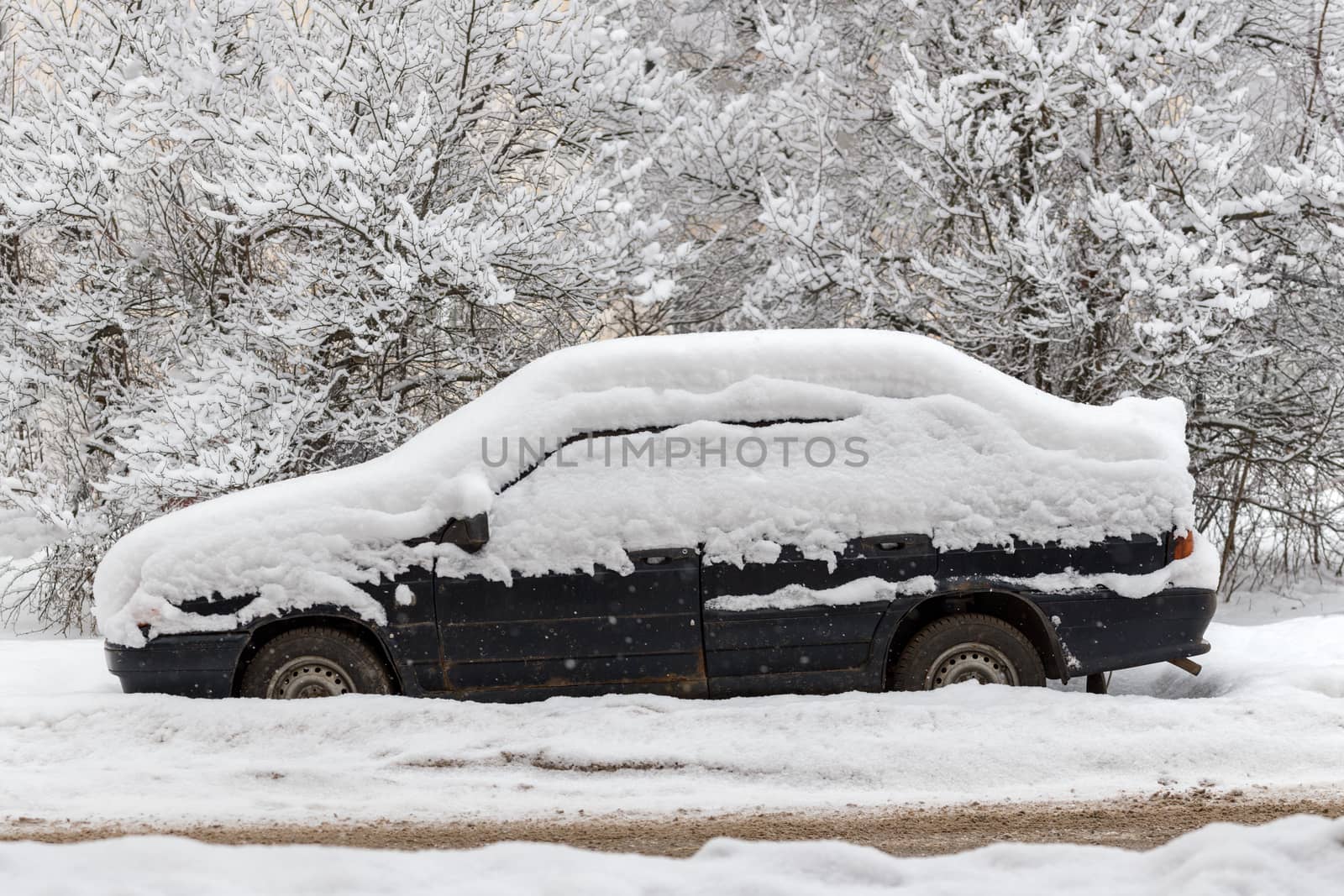 Old dirty car covered by thick snow layer with selective focus.