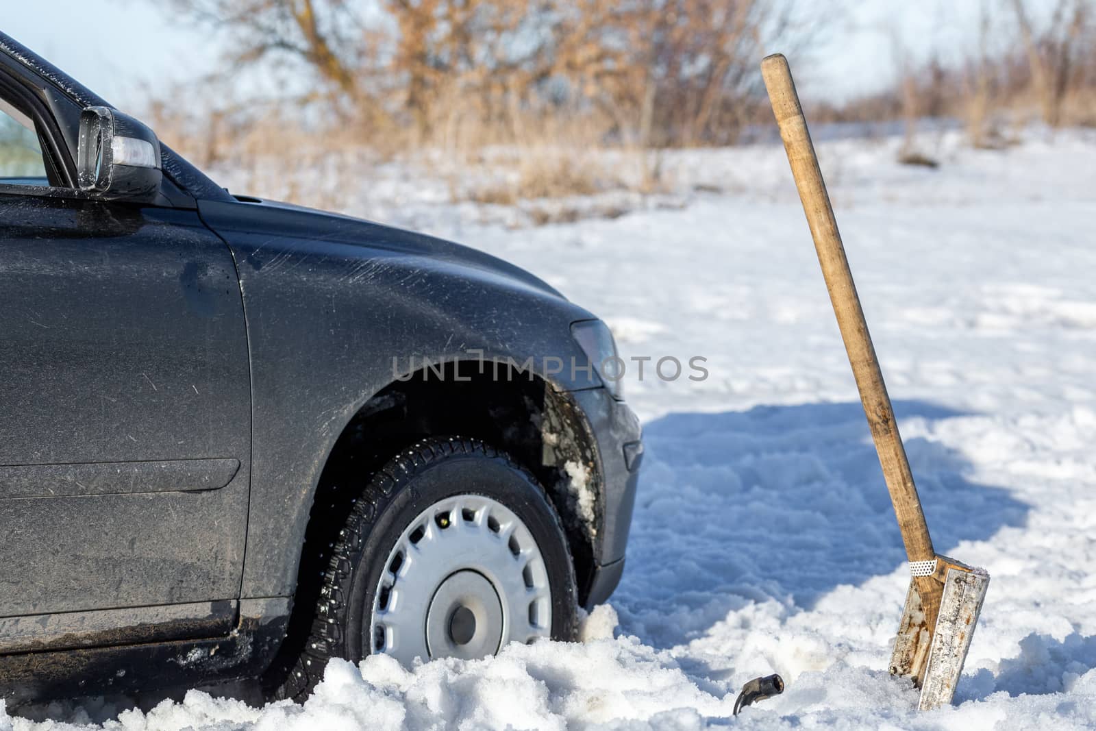 car stuck in snow offroad at daylight with shovel and selective focus by z1b