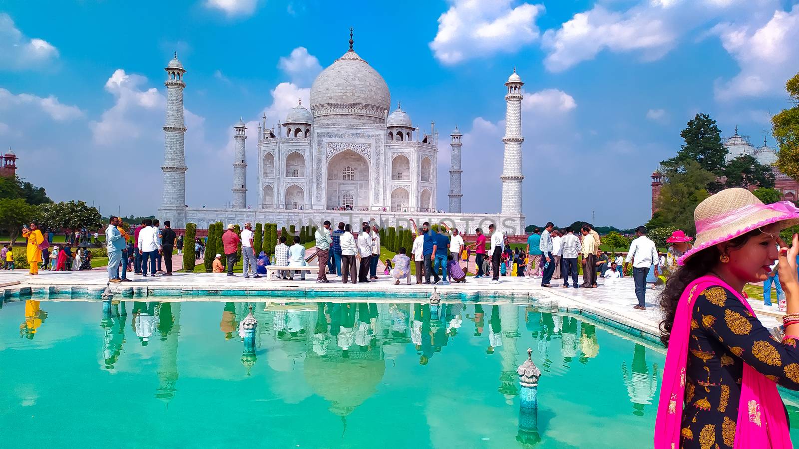 Front view of Taj Mahal with fountain pond in the foreground in sunny summer day. Taj Mahal tomb with reflection in the water at blue dramatic sky in Agra, Uttar Pradesh, India South Asia Pac May 2019