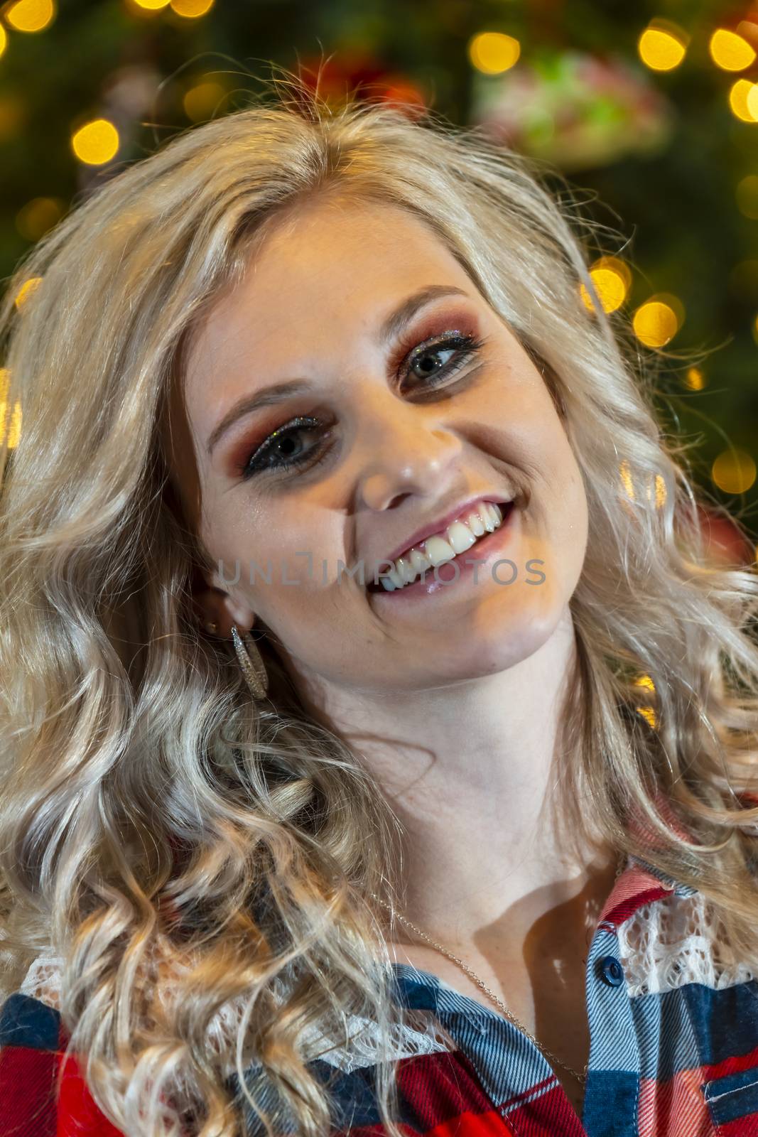 A gorgeous blonde model enjoys the holiday season at home with a Christmas tree and presents