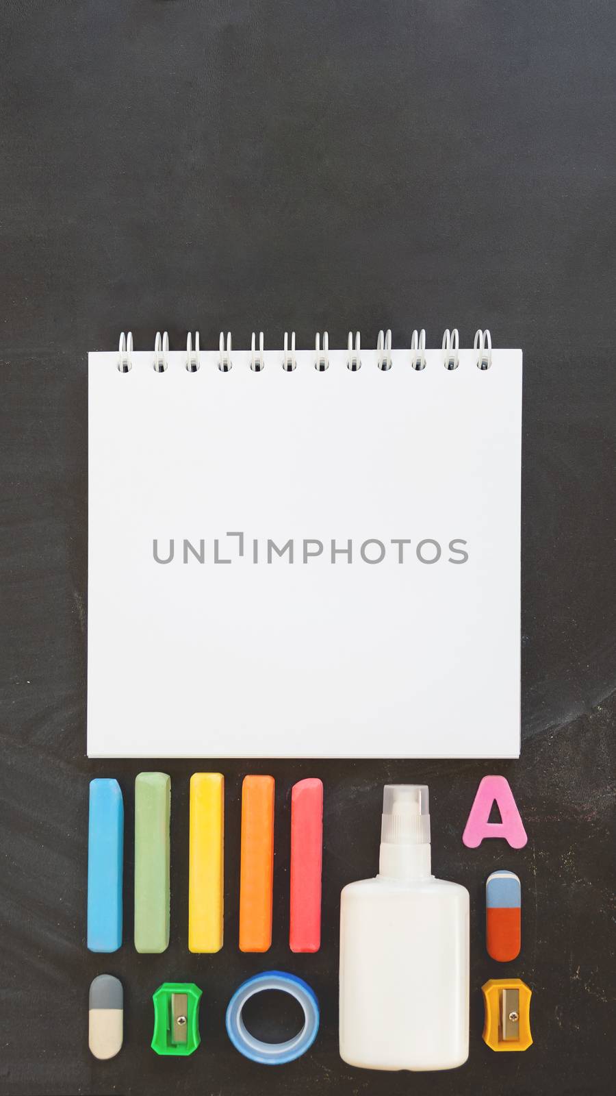 Top view on colorful stationery. Back to school flat lay concept. Vertical blackboard background with copy space. 9-16 ratio for mobile applications.