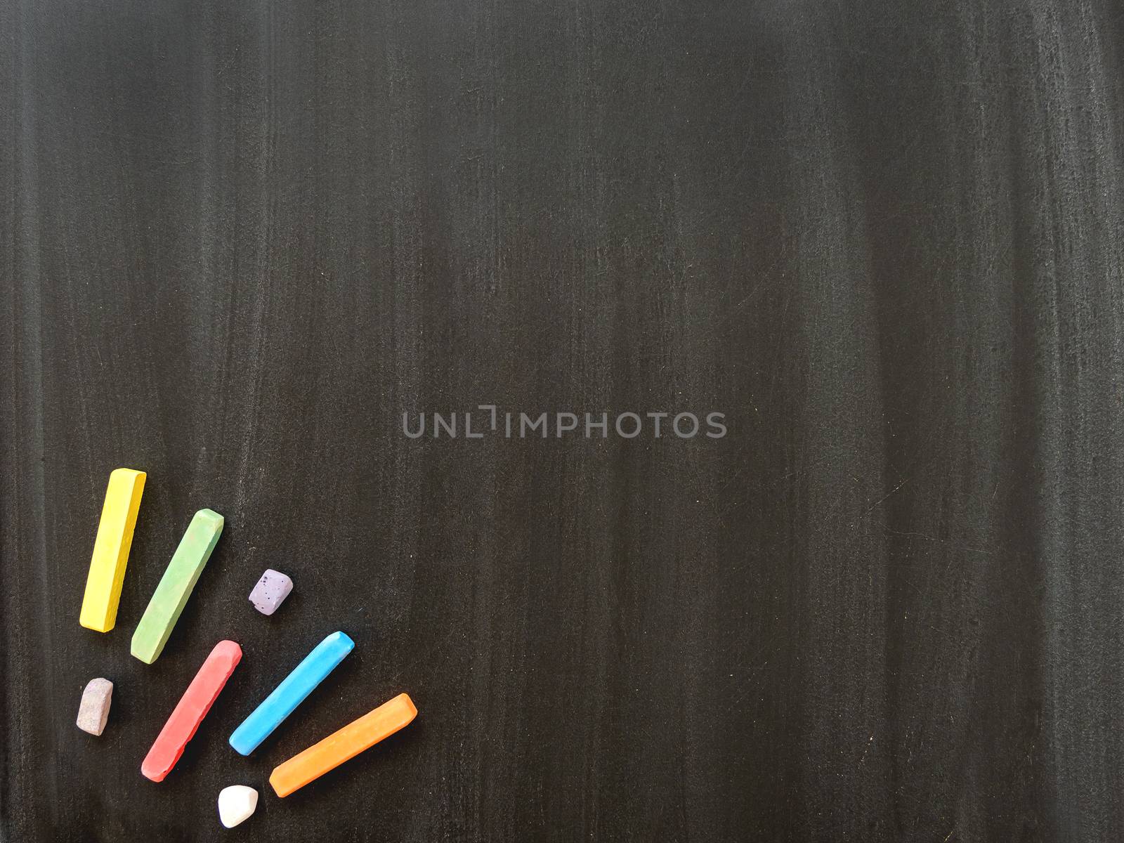 Top view on school blackboard with colorful chalks. Black dirty chalkboard with white chalk traces.. Back to school concept background with copy space.