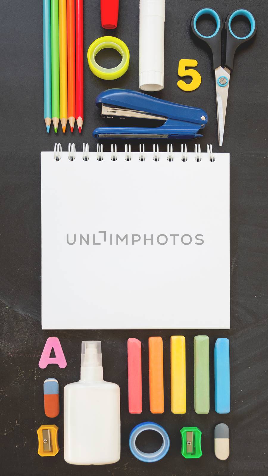 Top view on colorful stationery. Back to school flat lay concept. Vertical blackboard background with copy space. 9-16 ratio for mobile applications.