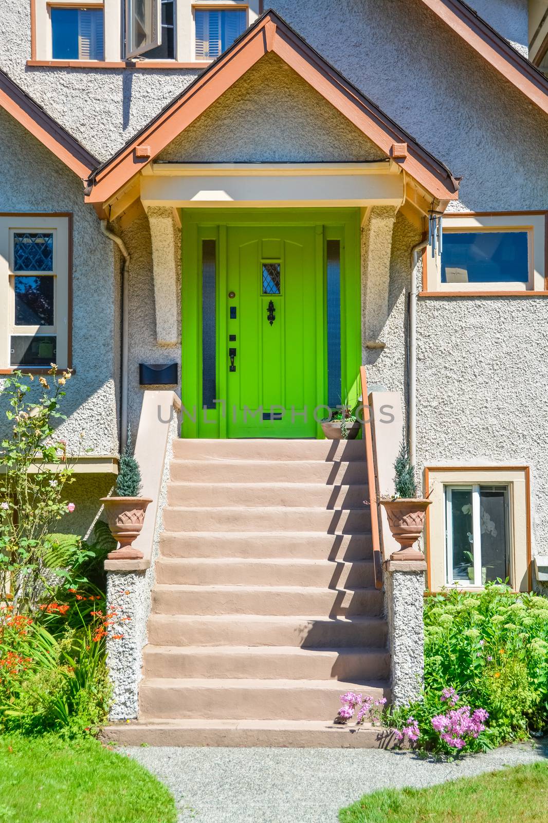 Green entrance door of snug family house under the porch with the doorsteps in front