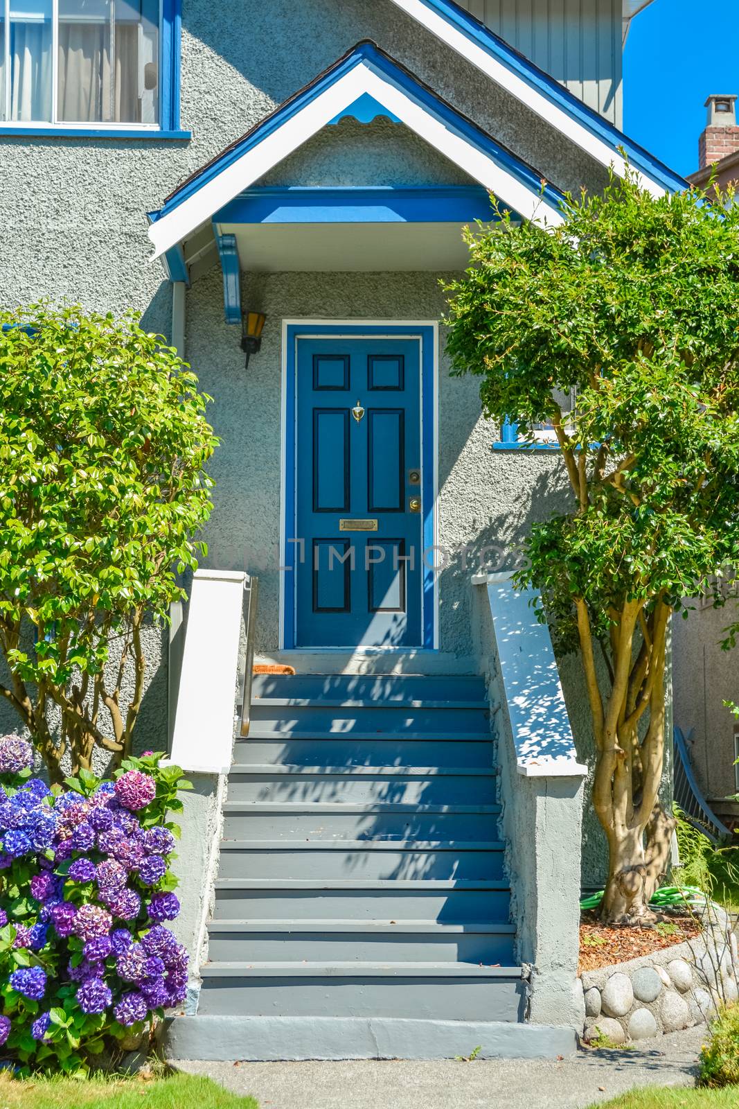 Blue entrance door of snug family house under the porch with the doorsteps in front