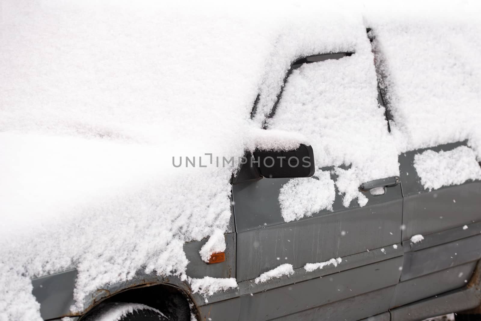 Dirty car covered by thick snow layer with selective focus.