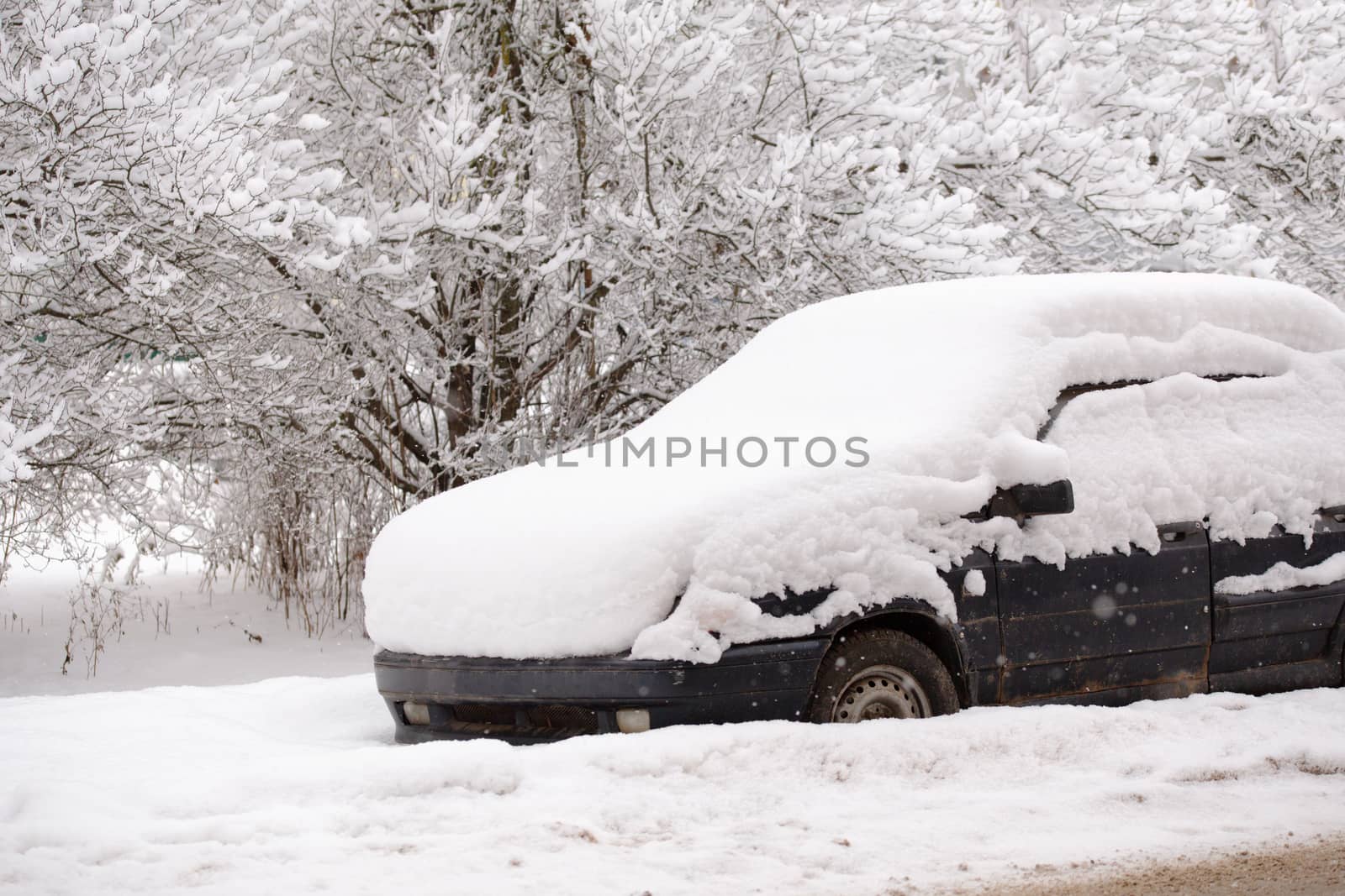 Old dirty car covered by thick snow layer with selective focus.