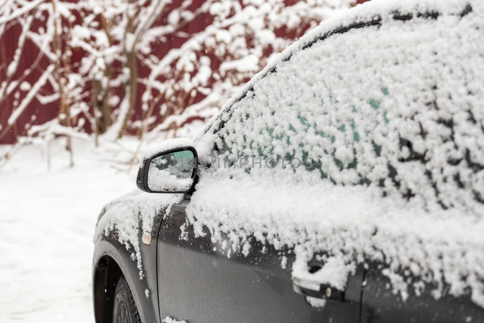 Dirty car covered by thick snow layer with selective focus.