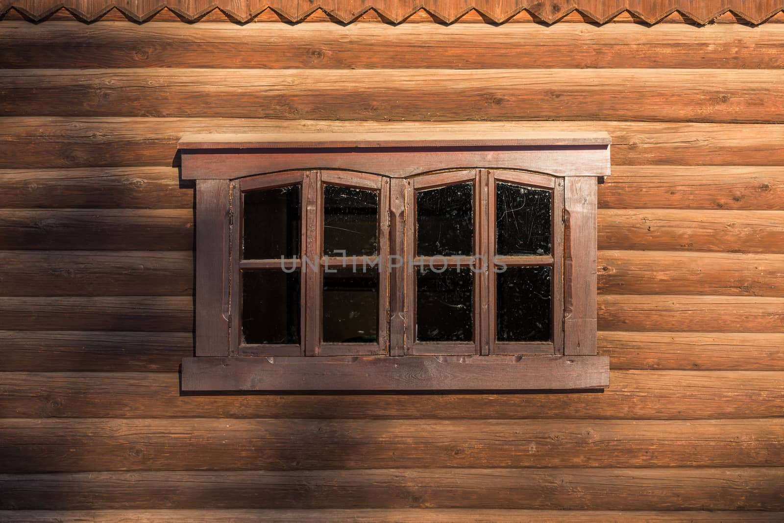log wall with one centered rectangular window under sunlight with blurry shadows