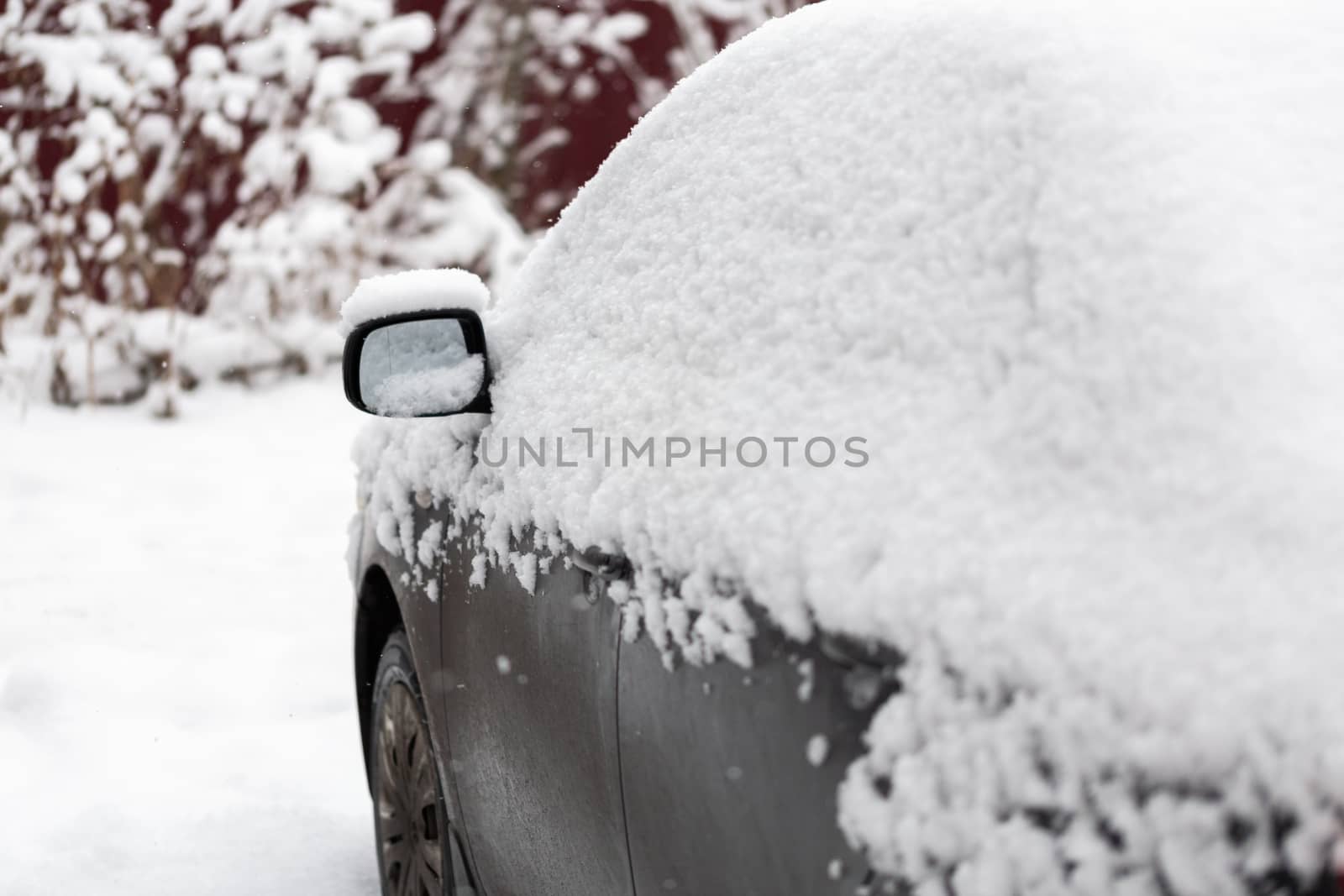 Dirty car covered by thick snow layer with selective focus.