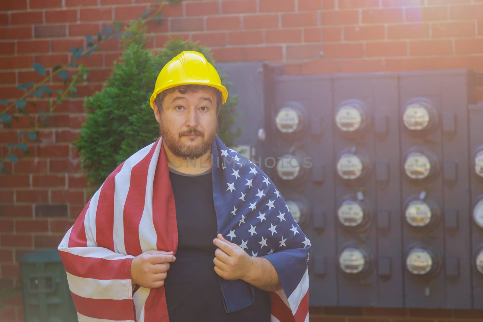 Worker man in safety yellow helmet protective standing against patriotic a federal holiday of United States America Flag Labor day concept