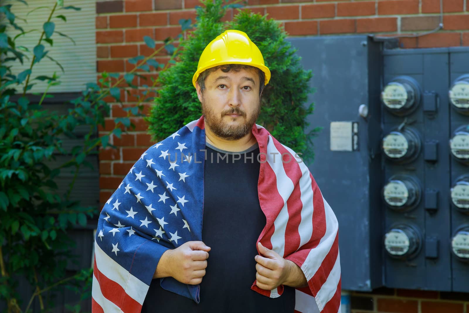 Labor day concept for worker in a yellow helmet with an American flag by ungvar