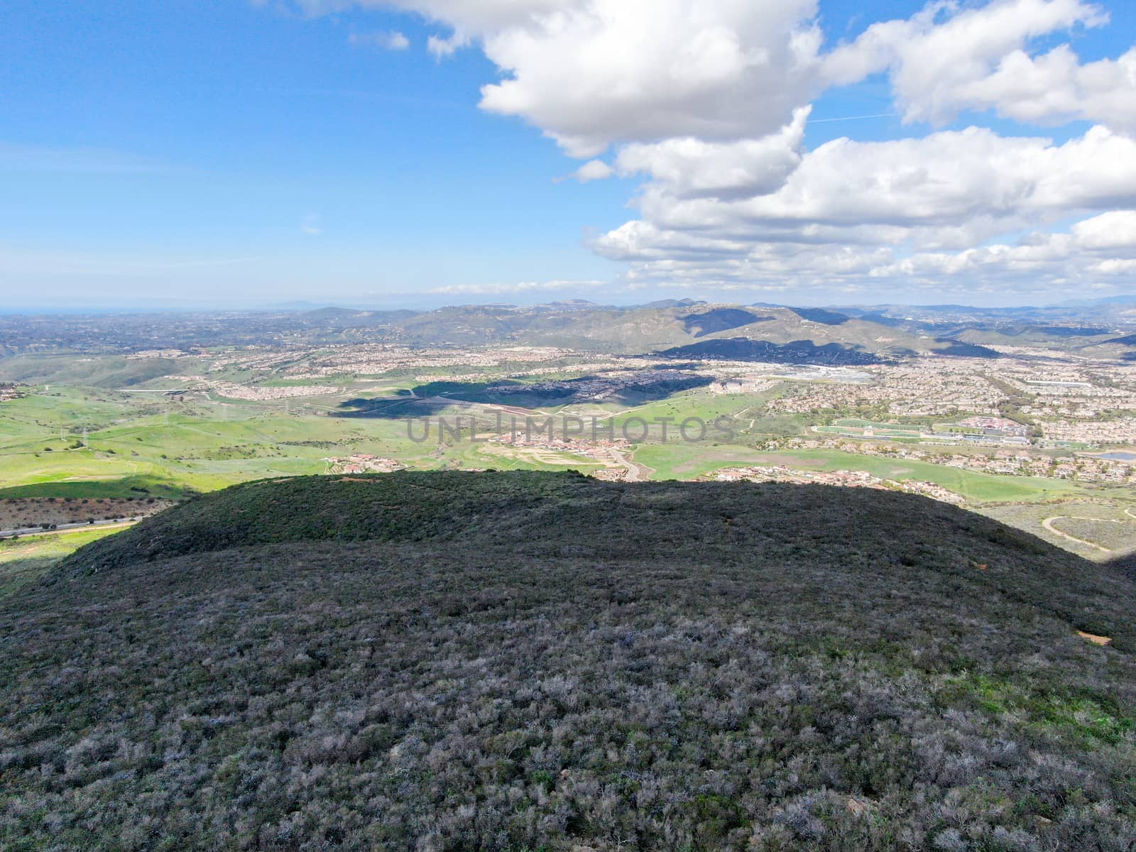 Aerial view of Black Mountain in Carmel Valley, San Diego, California, USA. Green dry mountain during sunny cloudy day with hiking trails, perfect for sport activity an leisure time..