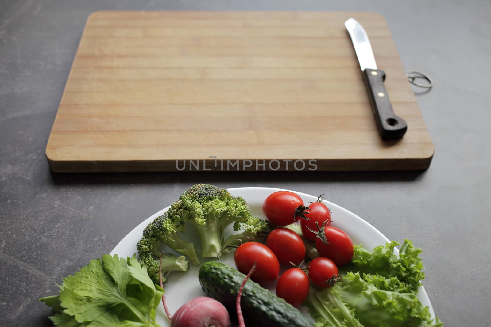 Fresh vegetables in a white plate on a gray table by selinsmo